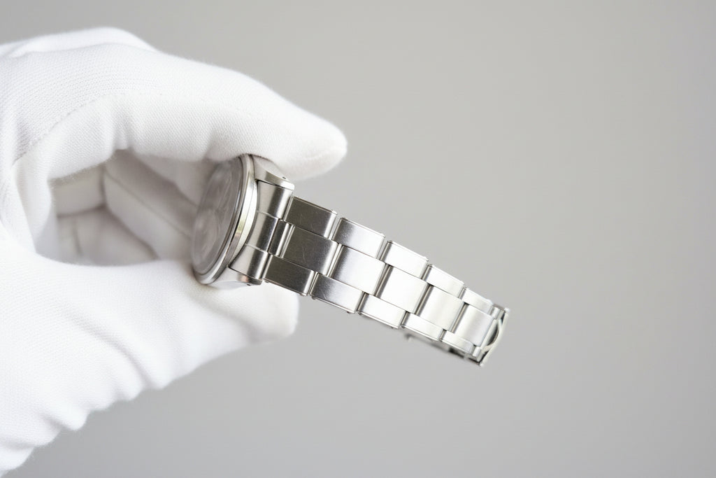 Metallic watch band held by a person with a blurred background