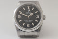 Rolex watch with black dial and silver case on a light gray background