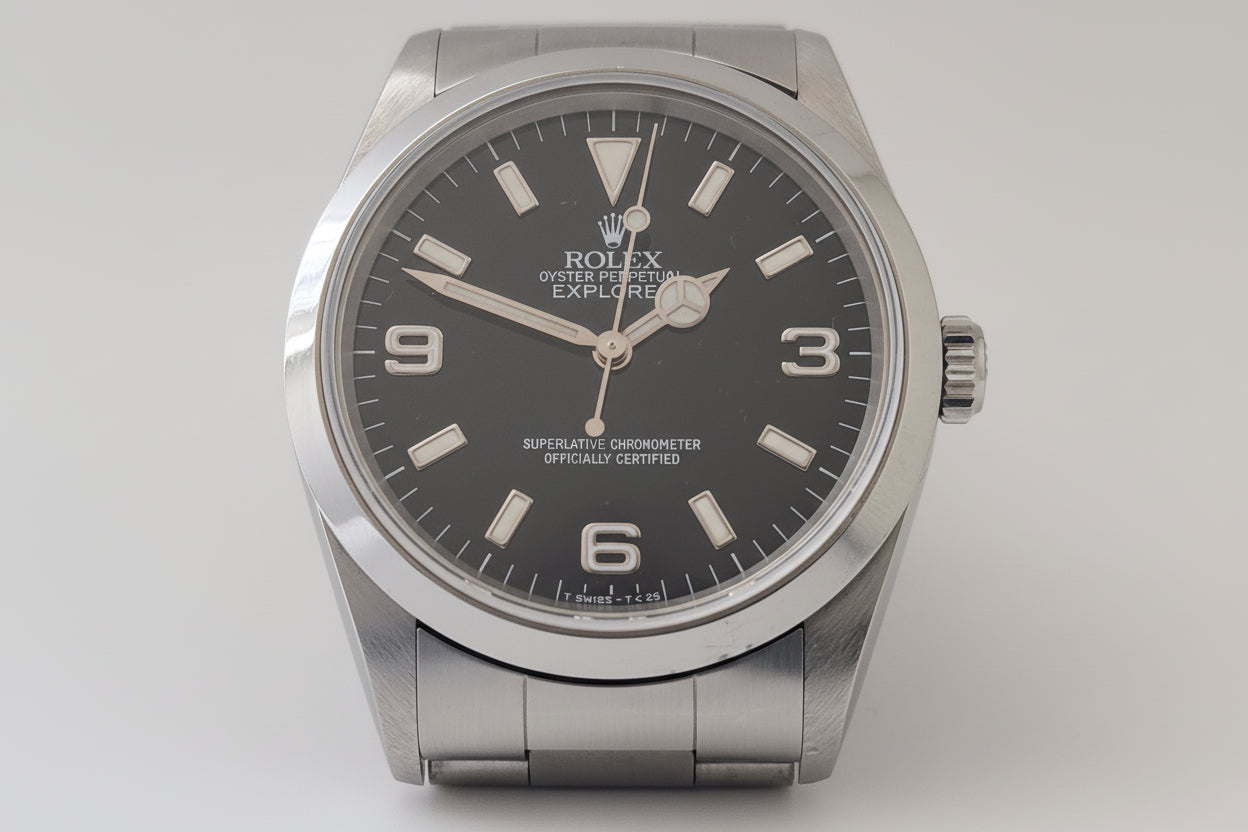 Rolex watch with black dial and silver case on a light gray background