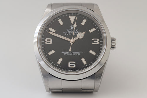 Rolex watch with black dial and silver case on a light gray background